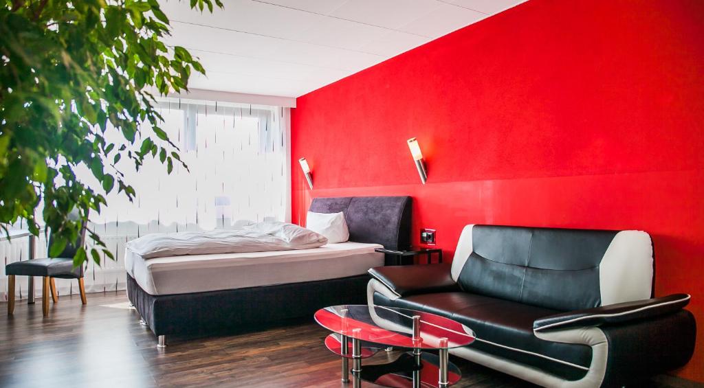 a bedroom with a red wall and a bed and a chair at City Hotel Heilbronn in Heilbronn