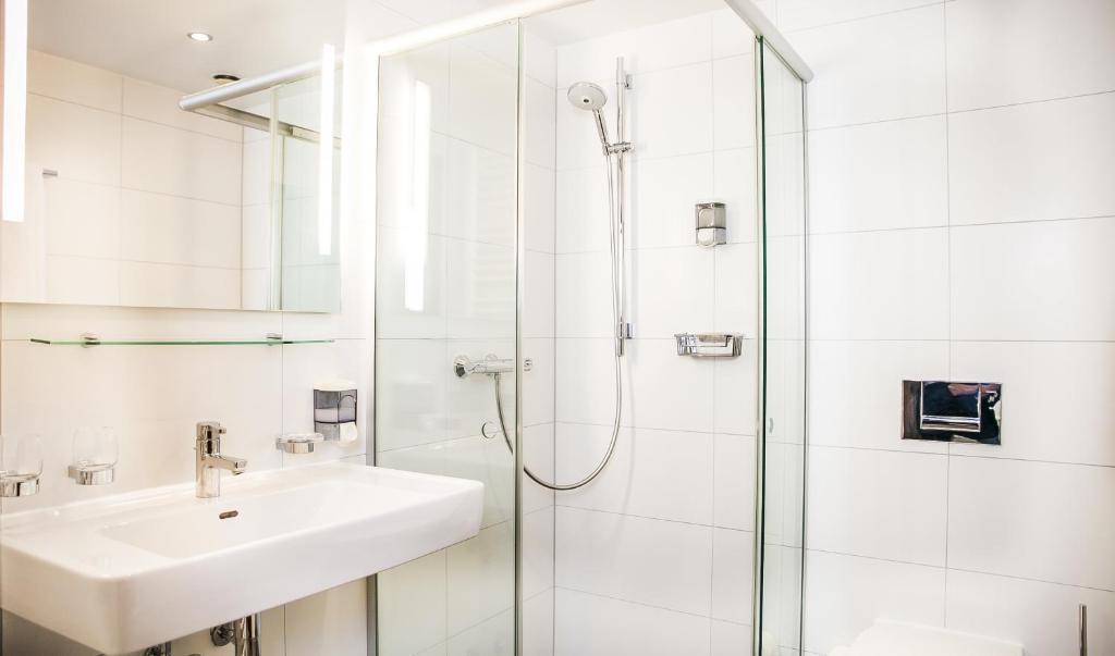 a white bathroom with a sink and a shower at City Hotel Heilbronn in Heilbronn