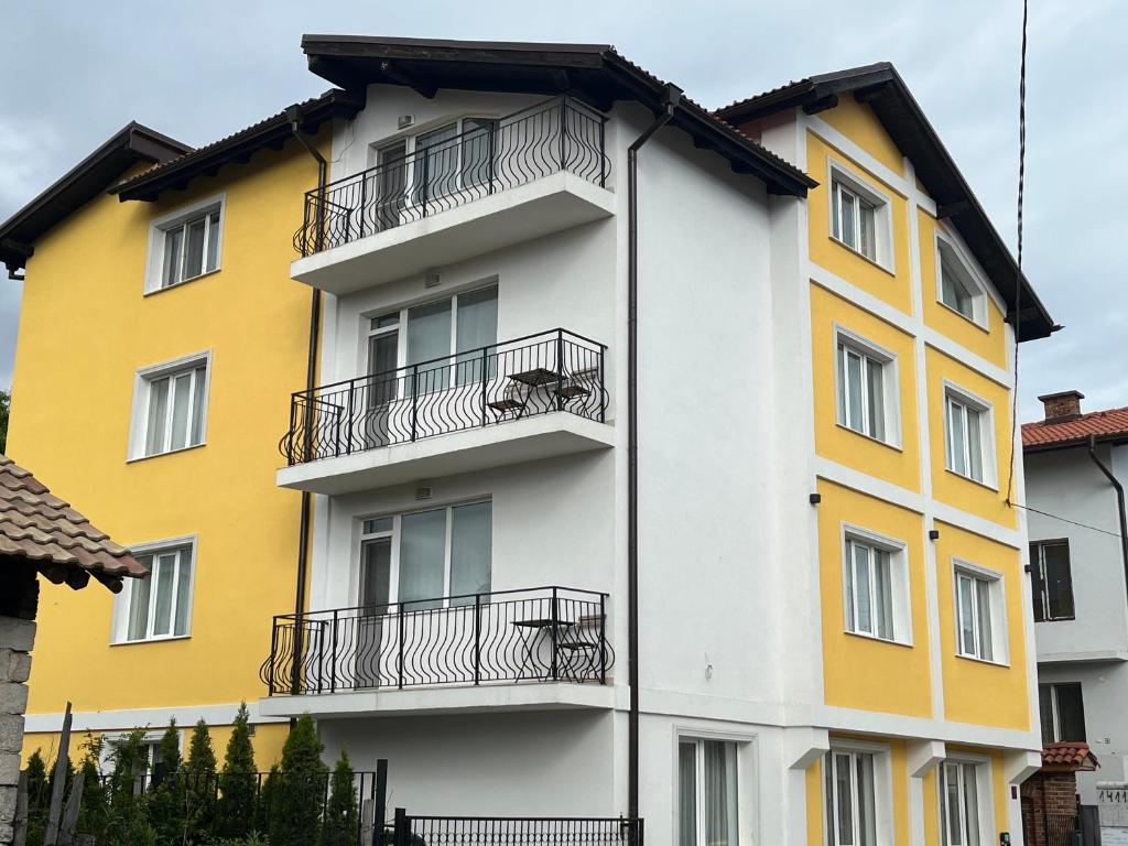 a yellow and white building with balconies at Horizont Dobrinishte in Dobrinishte