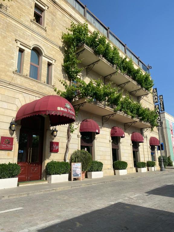 a building with red umbrellas and plants on it at Shah Palace Luxury Museum Hotel in Baku