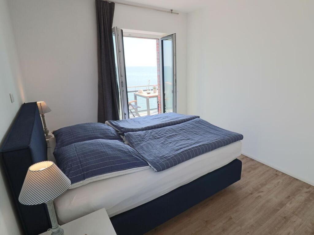 1 cama con almohadas azules en una habitación con ventana en Sea eagle in the Molenhuus, en Kappeln