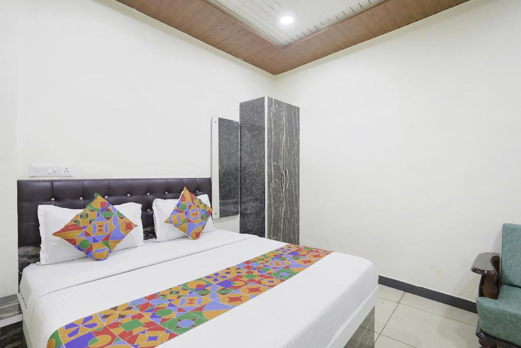 FabExpress Sai Palace في رايبور: غرفة نوم مع سرير أبيض كبير مع وسائد ملونة