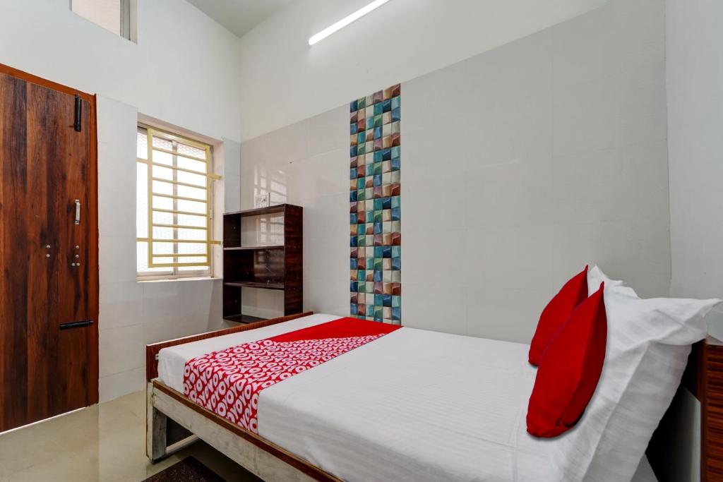 - une chambre avec un grand lit et des oreillers rouges dans l'établissement OYO Pothini Palace, à Palni