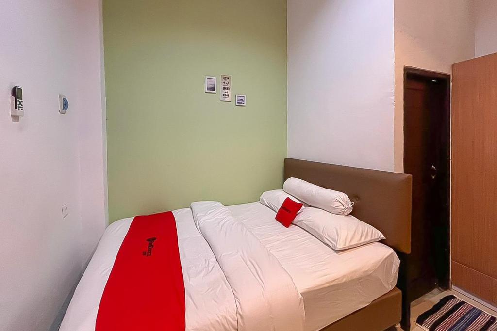 Un dormitorio con una cama con una capa roja. en RedDoorz syariah near Universitas Mulawarman, en Samarinda