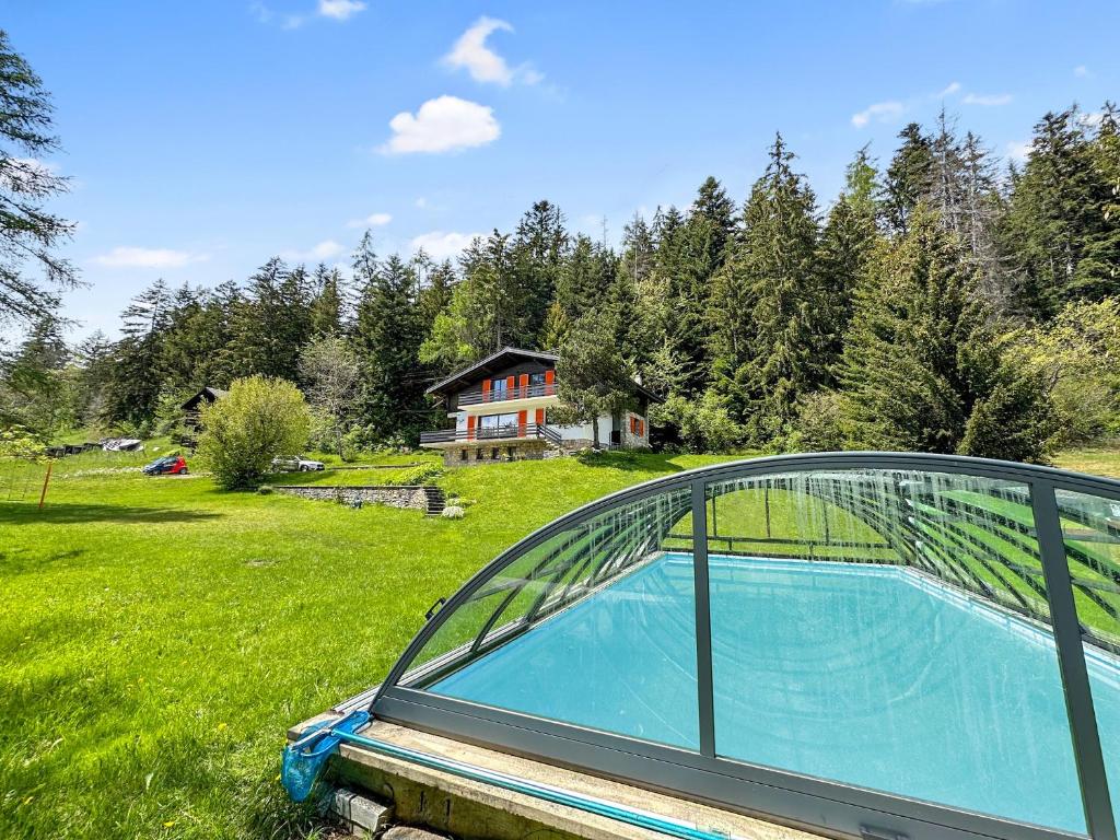 una piscina en un campo con una casa en Chalet Familial Les Girolles aux portes d'Anzère en Arbaz