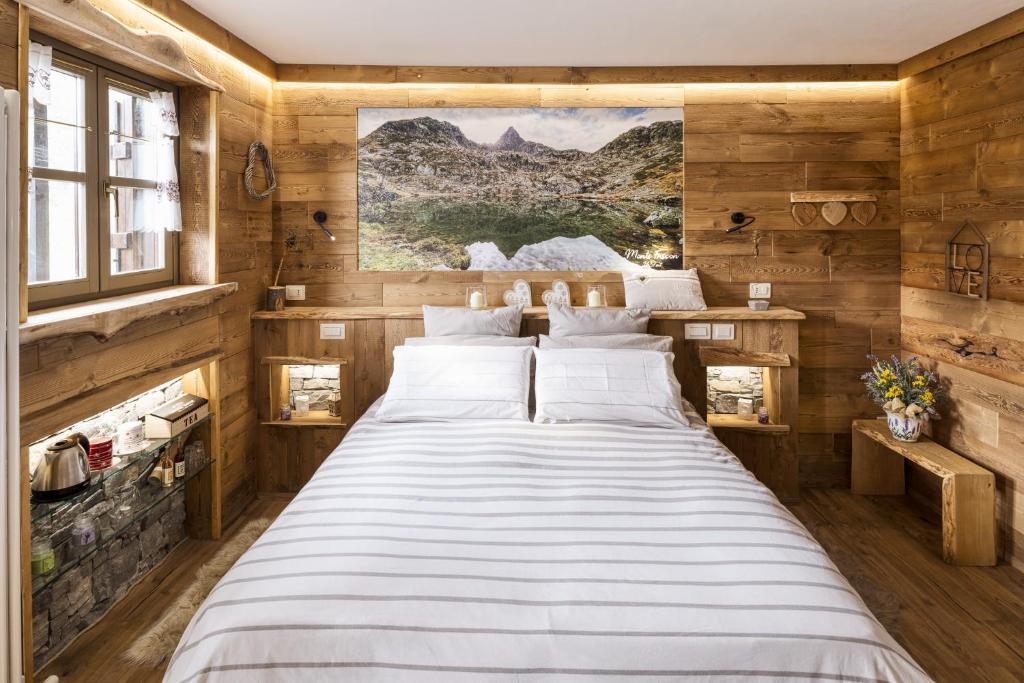 - un grand lit dans une chambre dotée de murs en bois dans l'établissement L'Arbergh Palanfrè, à Vernante