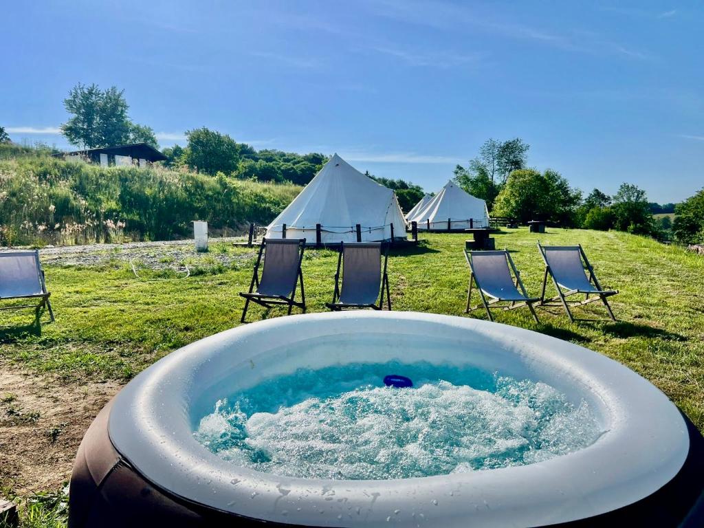 a bath tub with chairs and tents in a field at Glamping Bieszczady z jacuzzi i basenem in Solina