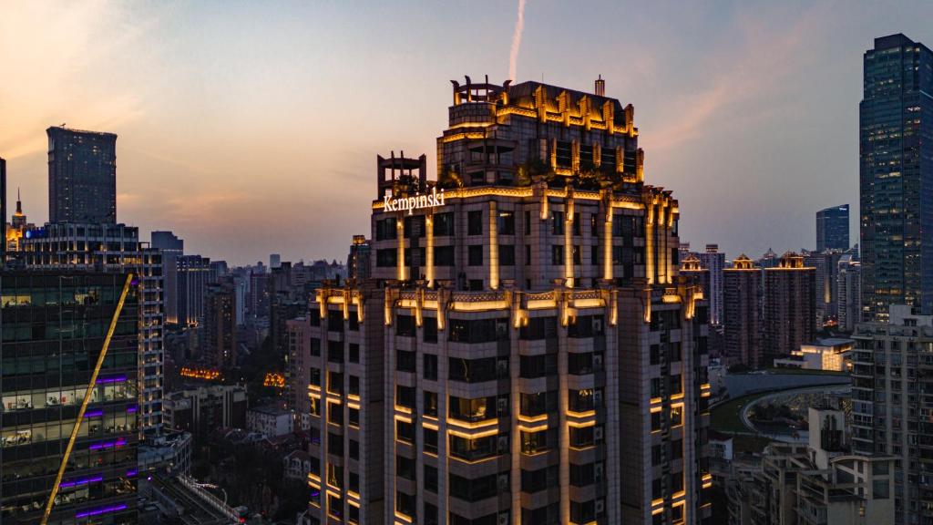 Kempinski The One Suites Hotel Shanghai Downtown في شانغهاي: مبنى طويل في مدينة عند غروب الشمس