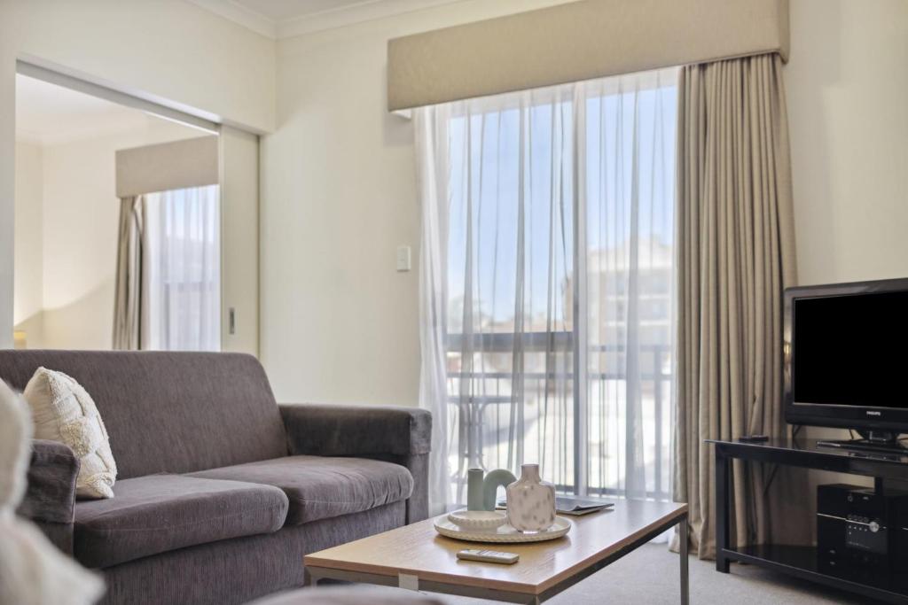 a living room with a couch and a large window at Spacious Apt in Northbridge with Pool in Perth