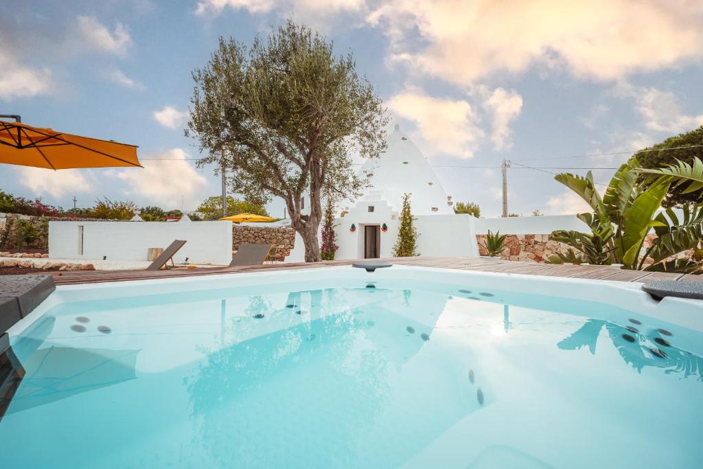 a swimming pool in a villa with an umbrella at TrulloMare & Pool - Housea in Polignano a Mare