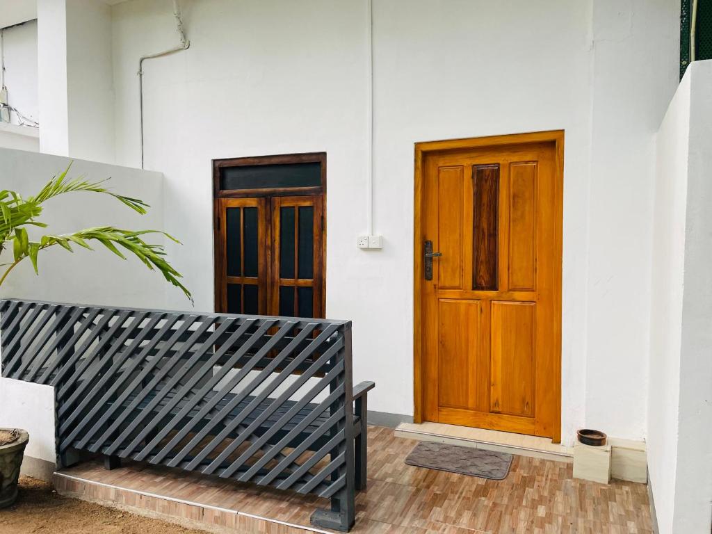 un banco frente a una puerta de madera en ZIMBAY Guest House, en Arugam Bay