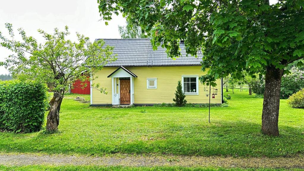 uma casa amarela num quintal com duas árvores em Nice holiday home in Balsta em Bålsta