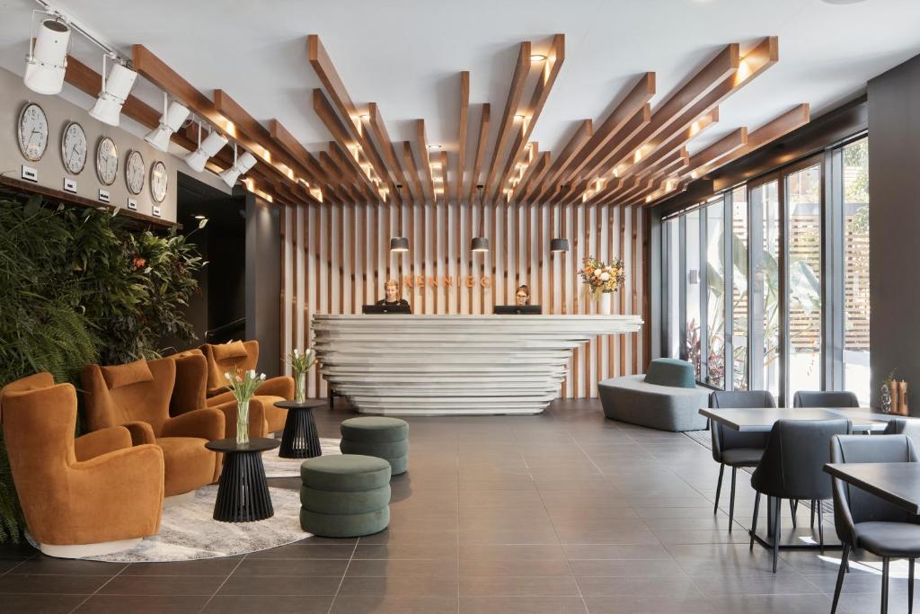a lobby with a waiting area with chairs and tables at Kennigo Hotel Brisbane, Independent Collection by EVT in Brisbane
