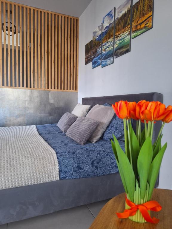 sypialnia z łóżkiem i stołem z kwiatami w obiekcie Apartament Górska Szarotka w Nowym Targu