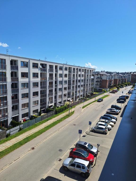 parking z samochodami zaparkowanymi przed dużym budynkiem w obiekcie Apartament Górska Szarotka w Nowym Targu