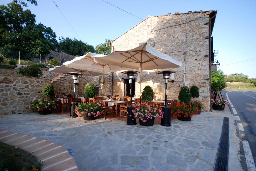 un patio al aire libre con mesas, sombrillas y flores en Locanda All'Andreas, en Montemerano