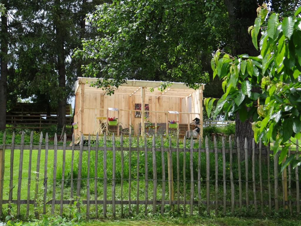 a dog sitting in front of a tent behind a fence at B&B Le bruissement in Bièvre