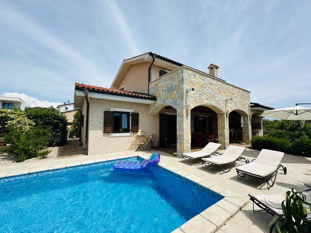a swimming pool with chairs and a house at Villa Seaside in Krk