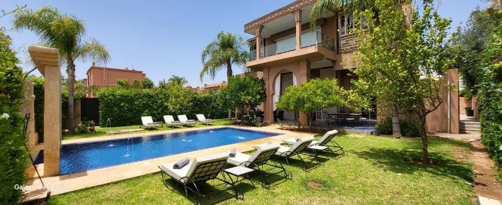 un patio con una piscina con sillas y un edificio en Villa Ayada, en Marrakech