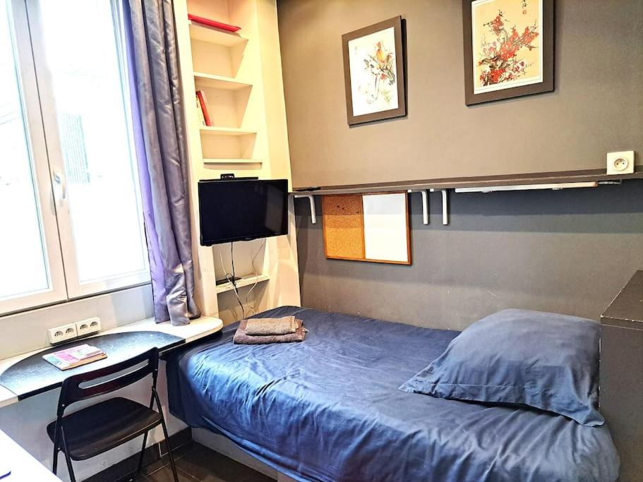 une chambre avec un lit, un bureau et une télévision dans l'établissement Studette Chabaud Rue, à Reims