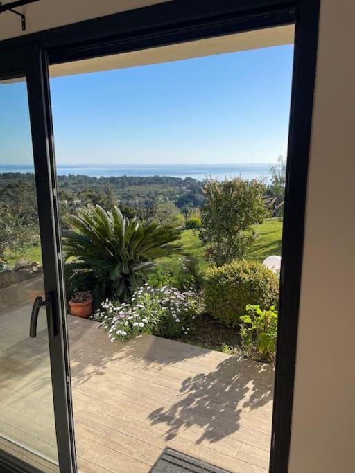 d'une porte coulissante en verre offrant une vue sur le jardin. dans l'établissement Rez de villa Machja vue mer et montagne à 2mn port, à Sari-Solenzara