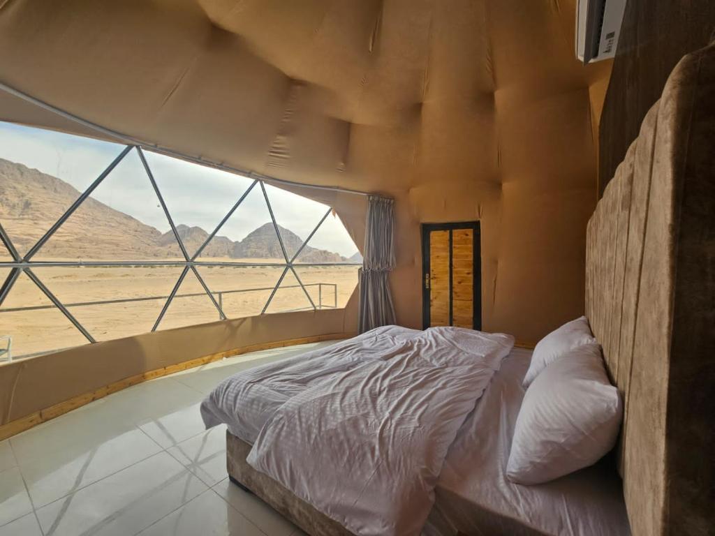 a bed in a room with a large window at Salma Desert Camp in Wadi Rum