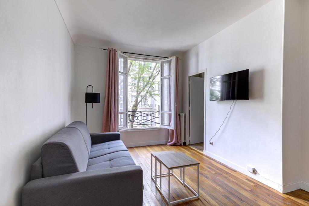 un salon avec un canapé et une télévision dans l'établissement 569 Suite Monceau - Superbe Appartement à Paris, à Paris