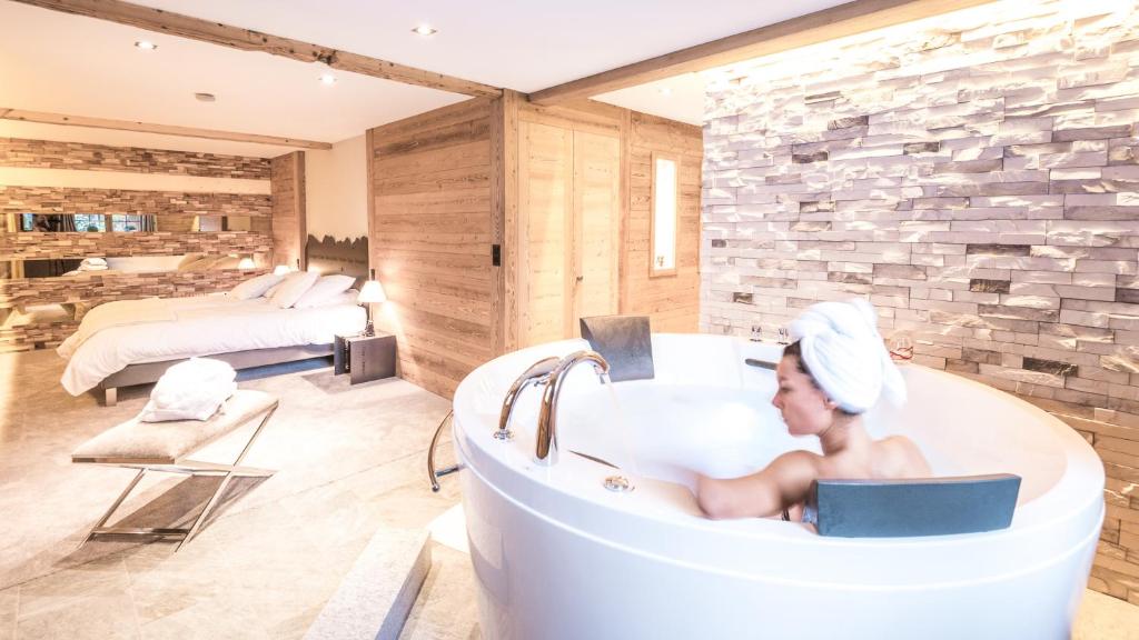 a woman sitting in a bath tub in a bedroom at Le Chalet de l'Atelier - Le Nord in Champéry
