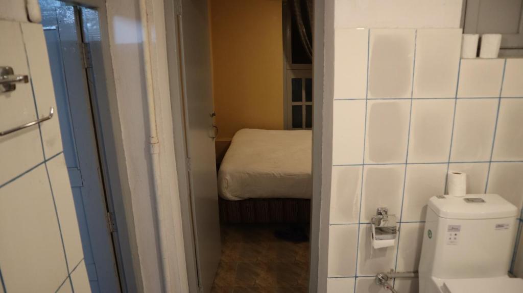a small bathroom with a toilet and a bed at Heranya Hostel in Kathmandu