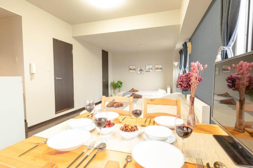 une salle à manger avec une table, des assiettes et des verres à vin dans l'établissement Green House Nakano Fujimicho - Vacation STAY 65279v, à Tokyo