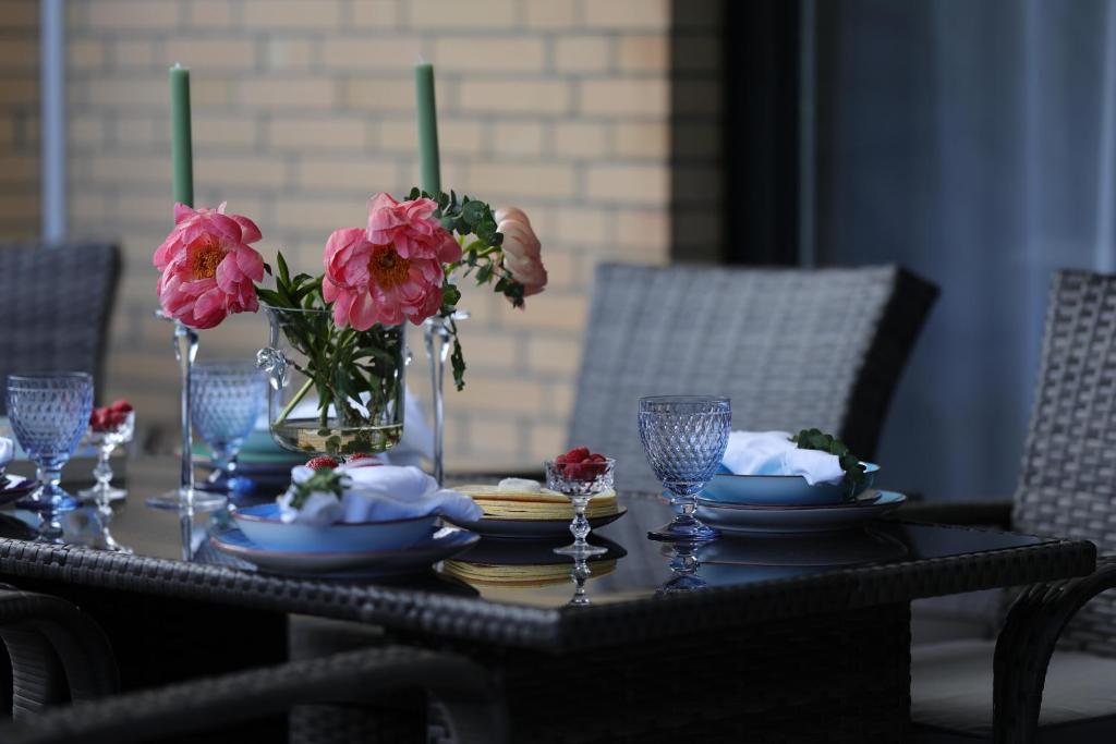 a table with plates and flowers in a vase at Ferienwohnung Strandoase inklusive Terrasse und Parkplatz - Sonnenseite in Scharbeutz