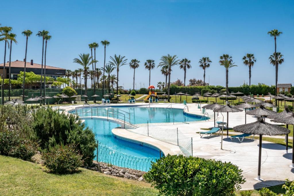 a large swimming pool with trees and palm trees at Kiko Las Americas in Isla Cristina