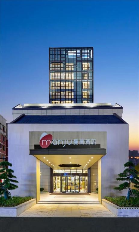 a building with a sign on top of it at Manju Hotel Huzhou Changxing Yufang Jiuhui City in Huzhou