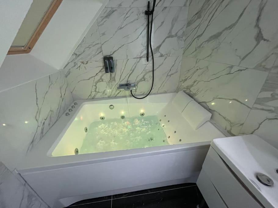 a white bath tub with a shower in a bathroom at Le Duplex Balnéo Maison climatisée in Saint-Martin-du-Tertre