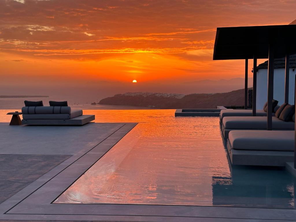 an infinity pool with a sunset in the background at Caldera's Memories in Imerovigli