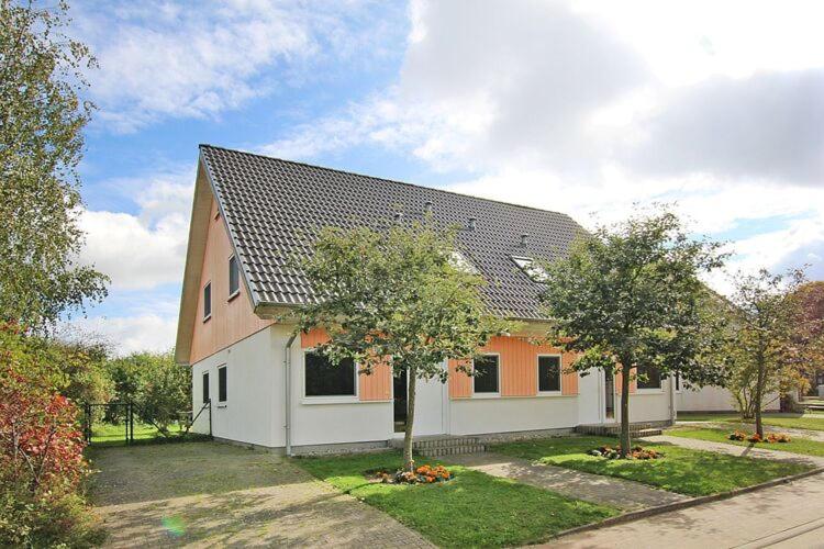 ein weißes und orangefarbenes Haus mit Bäumen davor in der Unterkunft Apartments home Vicky Appartements Wildsch nau Niederau in Niederau