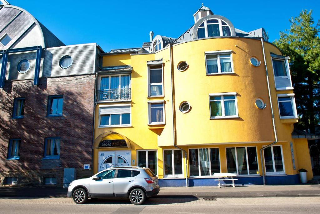 ein vor einem gelben Gebäude geparkt in der Unterkunft Hotel Georg in Witten