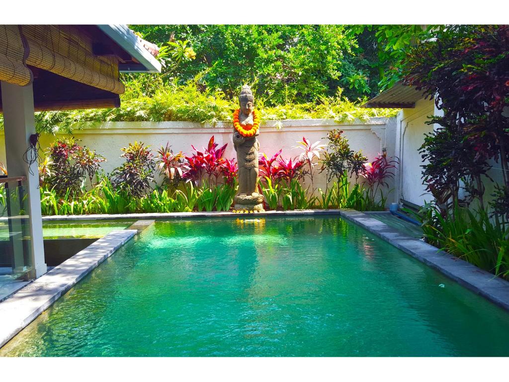 a small swimming pool with a fountain in a yard at Juada Garden in Seminyak