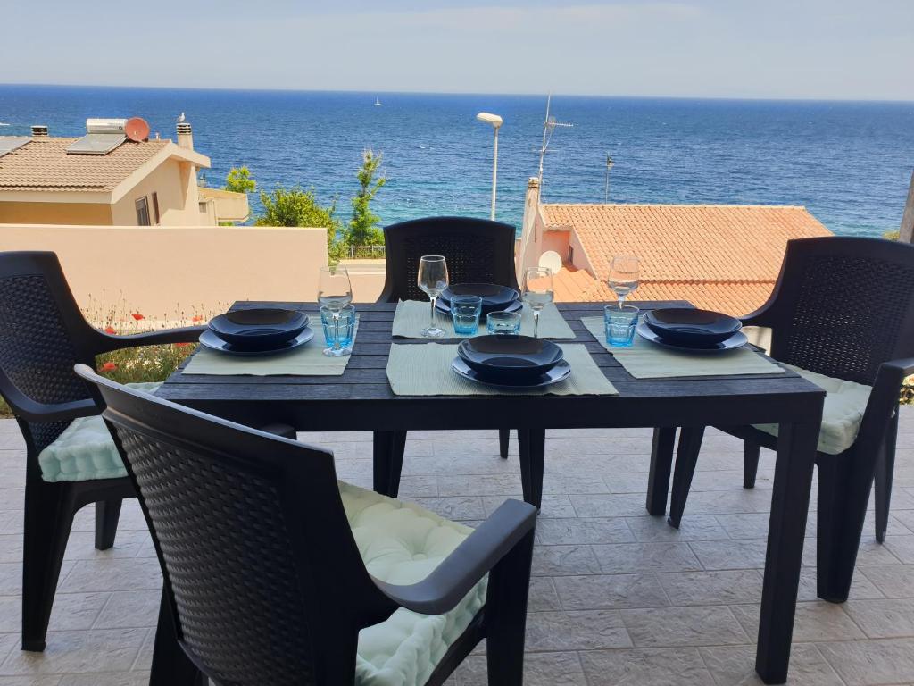 a table with chairs and a table with a view of the ocean at Samy house in Castelsardo