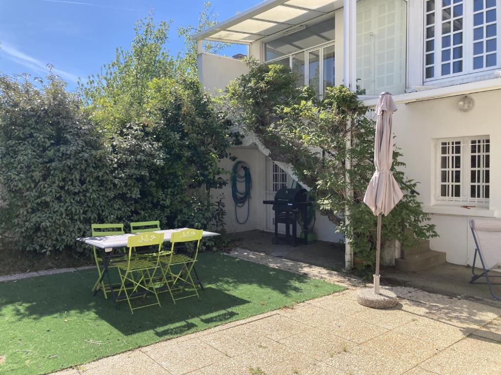 un patio avec un parasol, une table et des chaises dans l'établissement Maison de ville a etage - TERRASSE - WIFI, à Les Sables-dʼOlonne