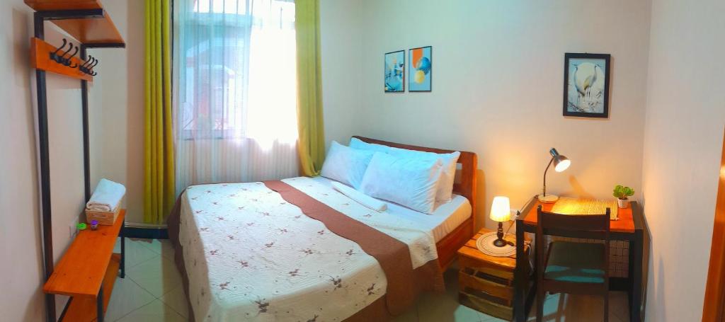 een kleine slaapkamer met een bed en een tafel met een lamp bij Dahari Home Hostel in Moshi