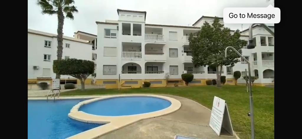 een groot appartementencomplex met een zwembad ervoor bij Villamartín PlazaGolf in Villamartin