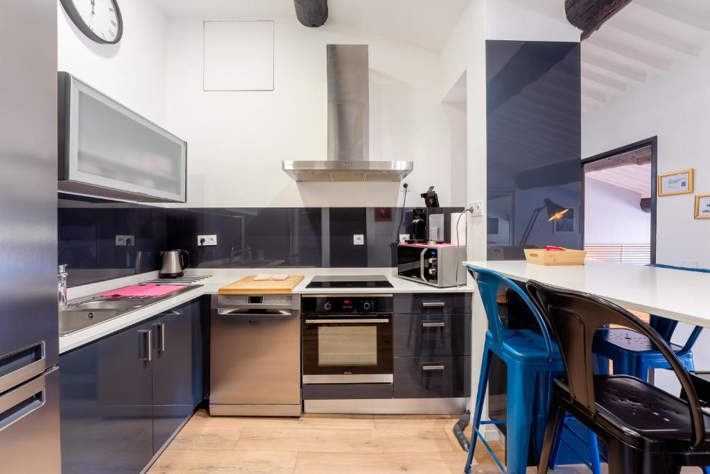 uma cozinha com electrodomésticos de aço inoxidável e armários azuis em Appart Hypercentre CLIM 2chb QuartierChic em Aix-en-Provence
