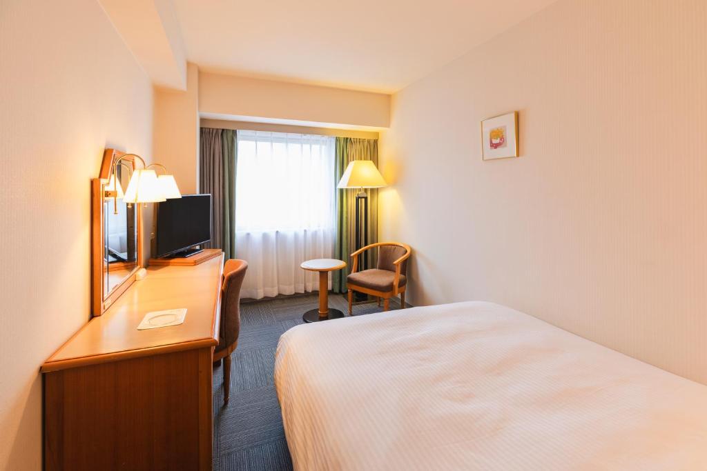新潟市にあるホテルサンルート新潟のベッドとテレビが備わるホテルルームです。