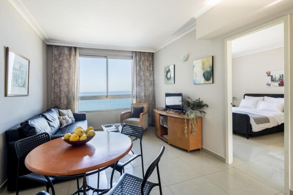 een woonkamer met een tafel en een kamer met een bed bij Almog Tower in Haifa