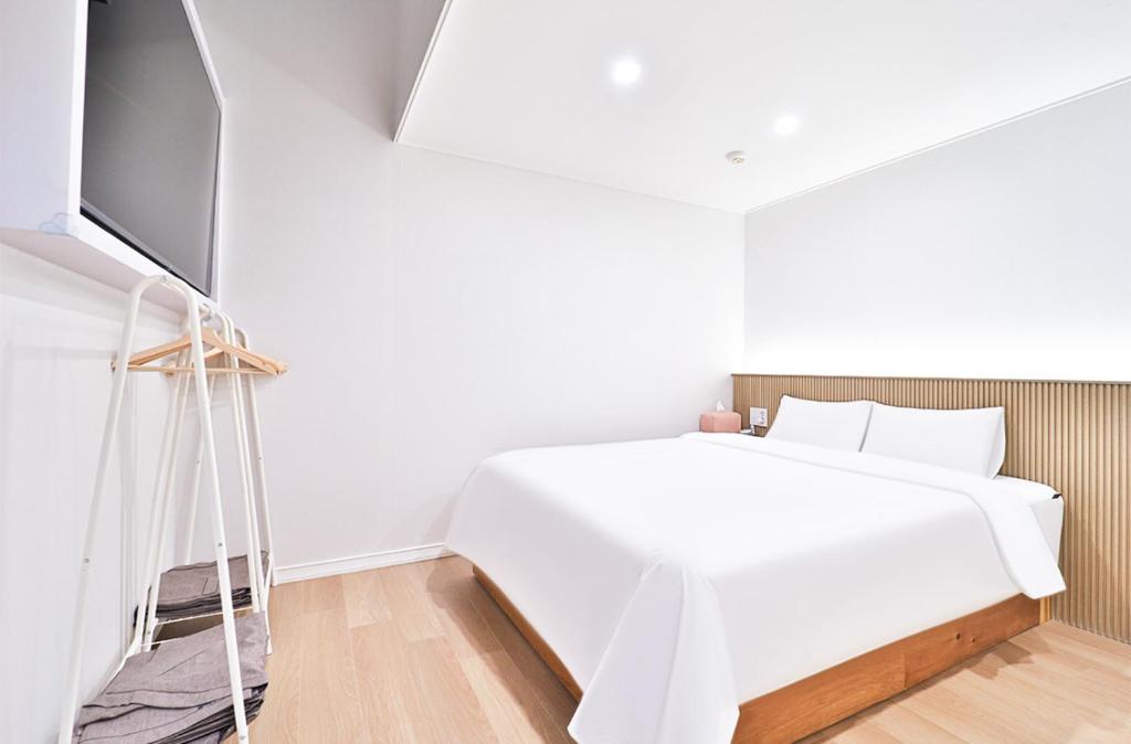 a bedroom with a white bed and a tv at Busan Gwangan Holic Story Hotel in Busan