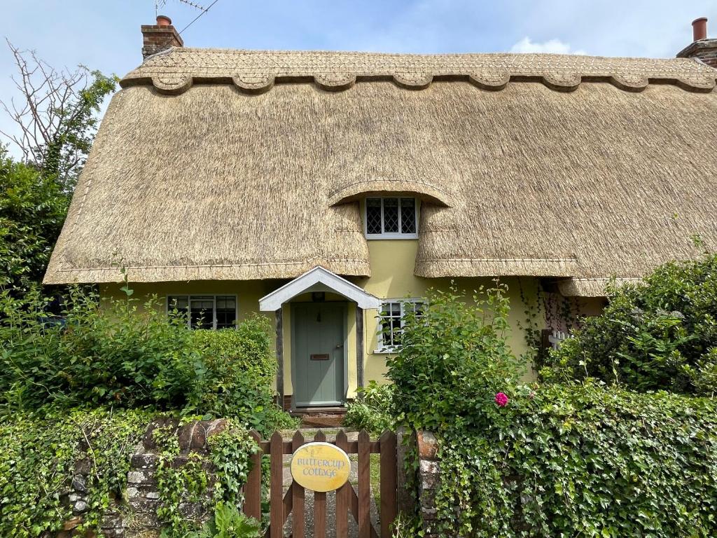 un cottage au toit de chaume avec un panneau en face de celui-ci dans l'établissement Buttercup Cottage, Hartest, à Hartest