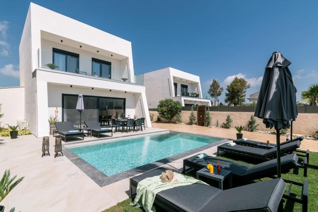 a villa with a swimming pool in front of a house at Sun White Villas in Laganas