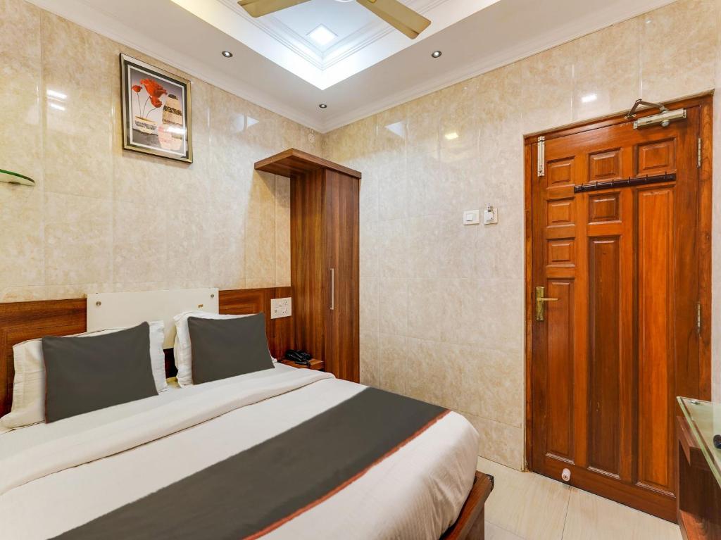 Schlafzimmer mit einem Bett und einer Holztür in der Unterkunft OYO Park Royal in Chennai