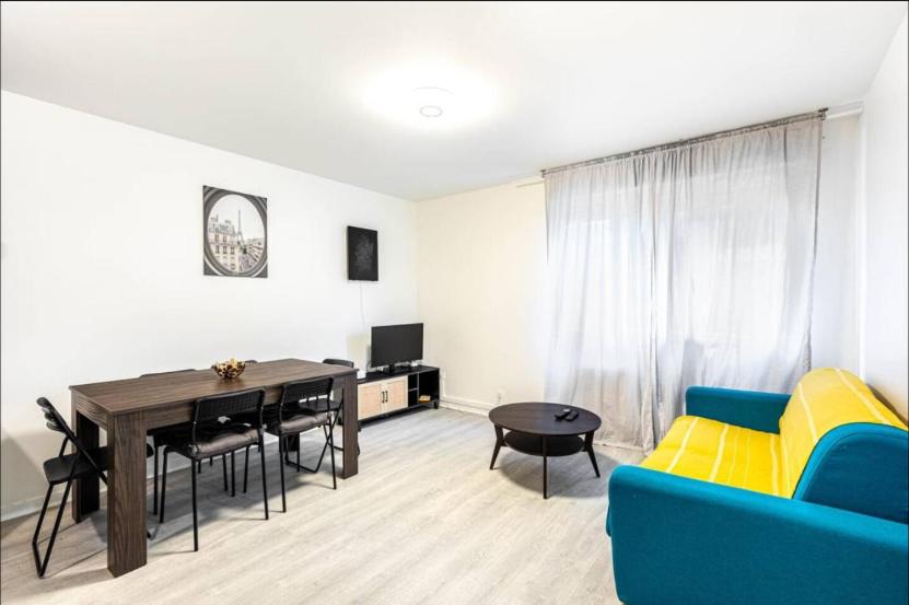 un salon avec un canapé bleu et une table dans l'établissement Jolie 2 pièces à Aubervilliers, à Aubervilliers